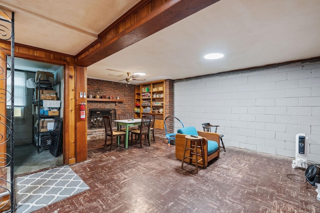 basement with ceiling fan and a brick fireplace