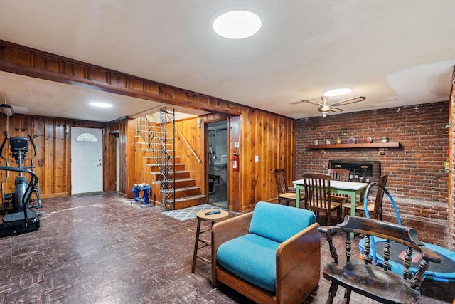 interior space with wood walls, ceiling fan, and brick wall