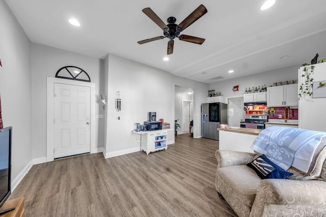 living room with ceiling fan, sink, and light wood-type flooring