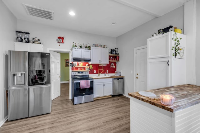 kitchen with appliances with stainless steel finishes, light wood-type flooring, white cabinetry, and sink