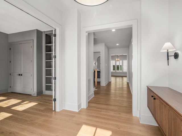 hallway with light hardwood / wood-style floors and a notable chandelier