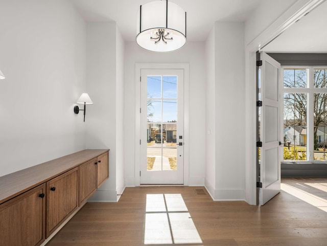 doorway with a notable chandelier and light wood-type flooring