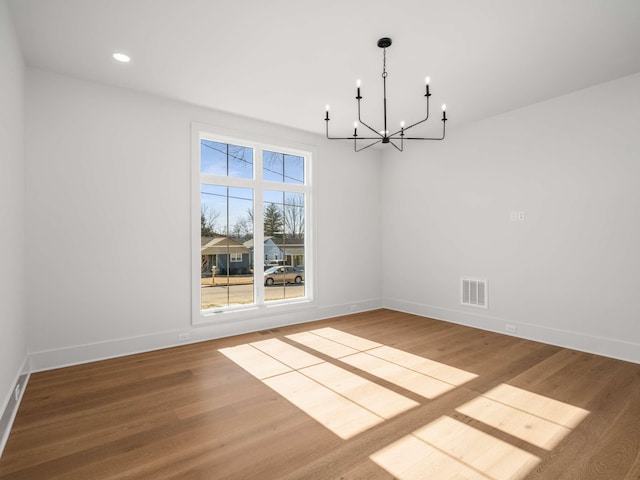 unfurnished dining area with wood-type flooring and an inviting chandelier