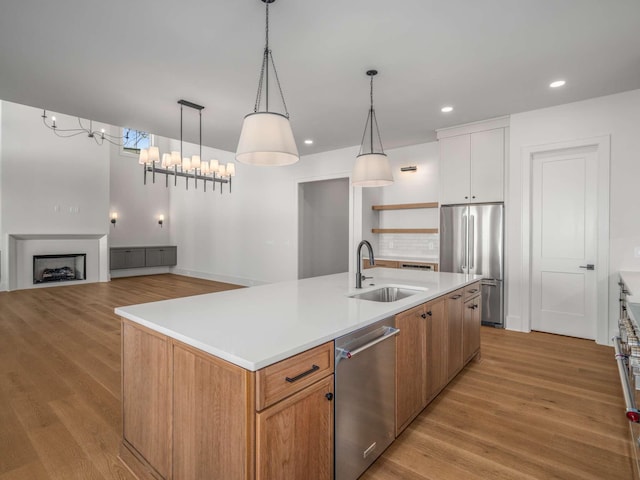 kitchen featuring white cabinetry, stainless steel appliances, sink, and an island with sink