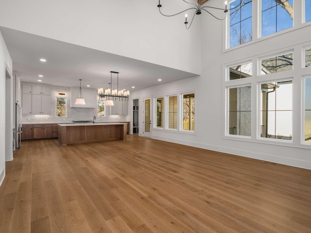 unfurnished living room with a notable chandelier, hardwood / wood-style floors, and sink