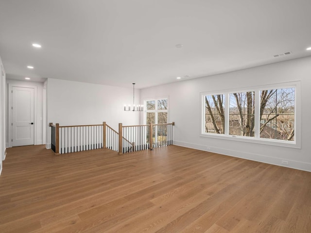 spare room featuring a chandelier and light wood-type flooring