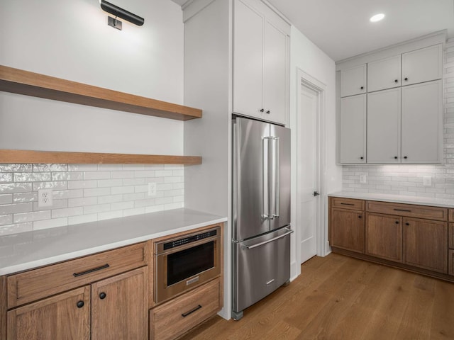 kitchen with tasteful backsplash, high end refrigerator, light hardwood / wood-style flooring, and white cabinets