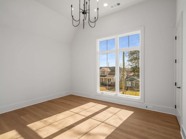 unfurnished dining area featuring vaulted ceiling, a wealth of natural light, a chandelier, and light hardwood / wood-style floors