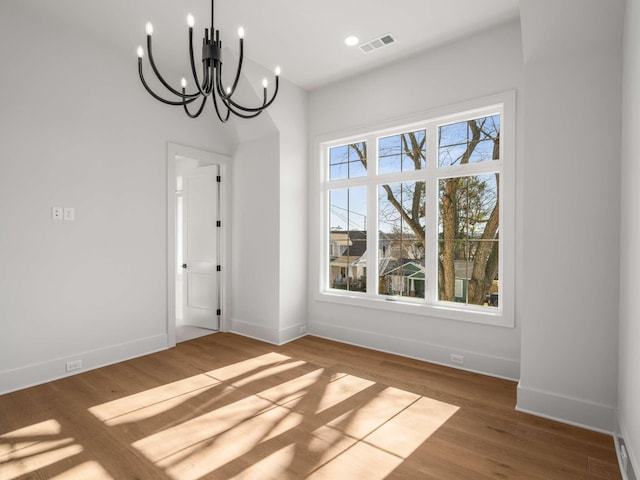 unfurnished dining area featuring wood-type flooring and a notable chandelier