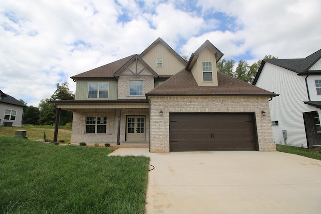 view of front of property with a porch, a garage, and a front lawn