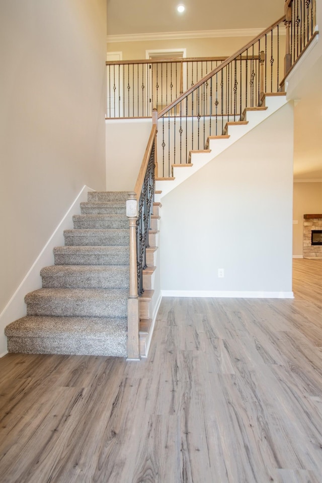 stairway featuring a fireplace, hardwood / wood-style floors, and ornamental molding