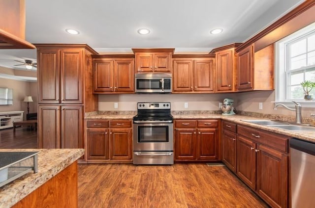 kitchen featuring hardwood / wood-style floors, sink, ceiling fan, ornamental molding, and appliances with stainless steel finishes