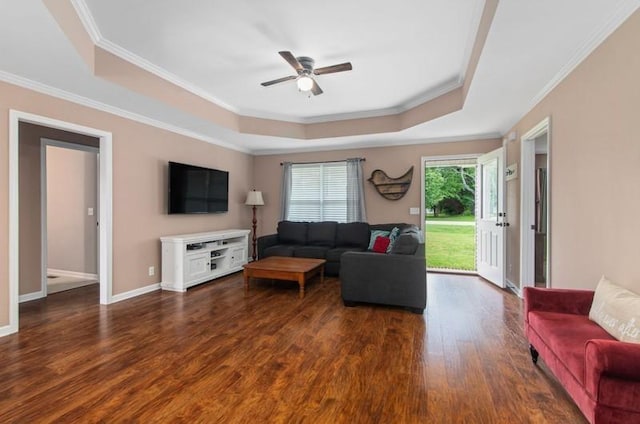 living room featuring dark hardwood / wood-style floors, a raised ceiling, ceiling fan, and ornamental molding