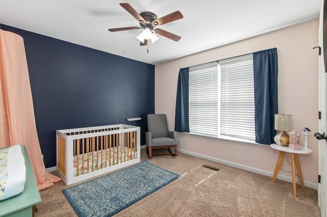 bedroom featuring a crib, carpet flooring, and ceiling fan