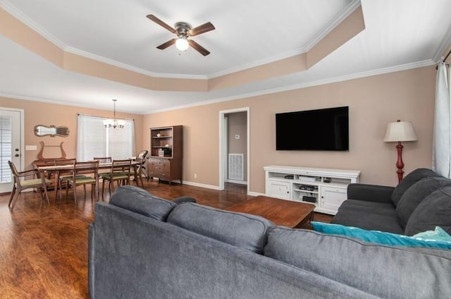 living room featuring ceiling fan with notable chandelier, dark hardwood / wood-style floors, a raised ceiling, and crown molding