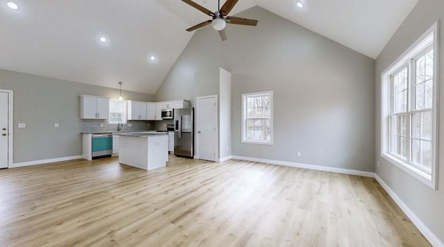 kitchen featuring appliances with stainless steel finishes, backsplash, a center island, white cabinetry, and hanging light fixtures