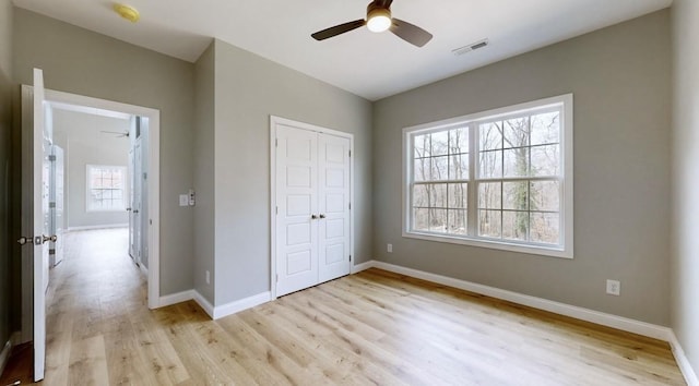 unfurnished bedroom featuring multiple windows, light hardwood / wood-style floors, a closet, and ceiling fan