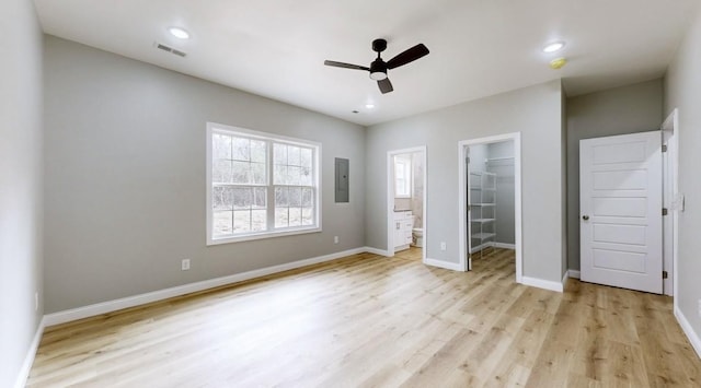 unfurnished bedroom with electric panel, ensuite bathroom, a walk in closet, ceiling fan, and a closet