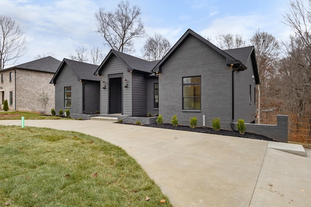 view of front facade with brick siding, a front lawn, and a shingled roof