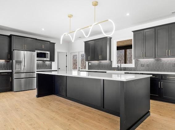 kitchen featuring stainless steel appliances, a kitchen island, and light countertops