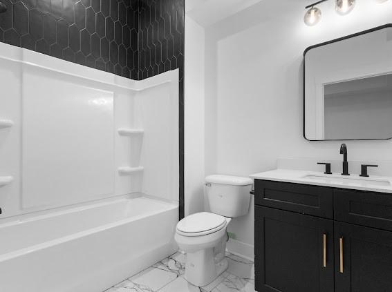 bathroom with baseboards, toilet, marble finish floor, tub / shower combination, and vanity