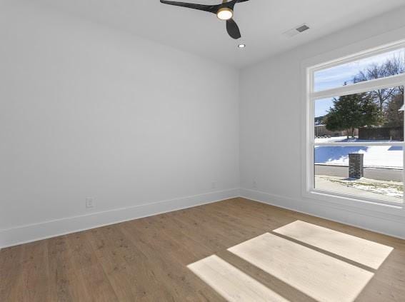 empty room with a ceiling fan, visible vents, baseboards, and wood finished floors