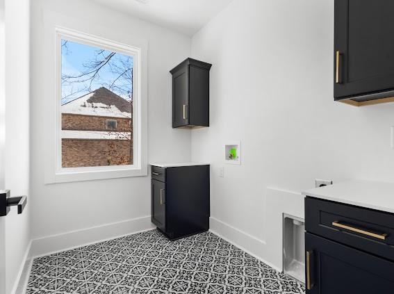 clothes washing area with hookup for a washing machine, cabinet space, and baseboards