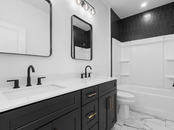 full bathroom with toilet, marble finish floor, a sink, and shower / tub combination