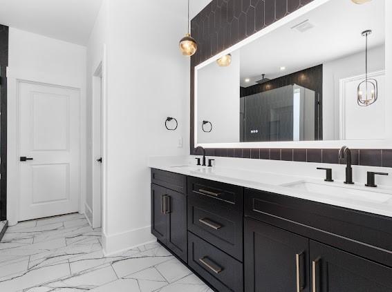 bathroom with double vanity, marble finish floor, baseboards, and a sink