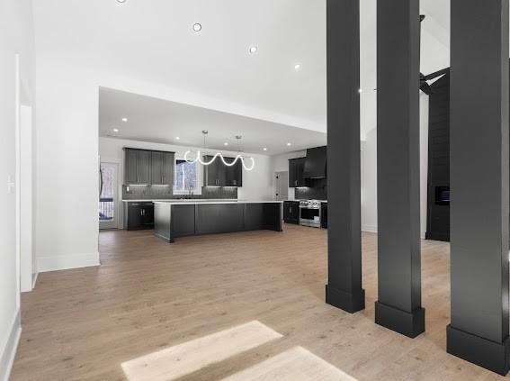 kitchen with a large island, light countertops, light wood-style flooring, open floor plan, and dark cabinetry