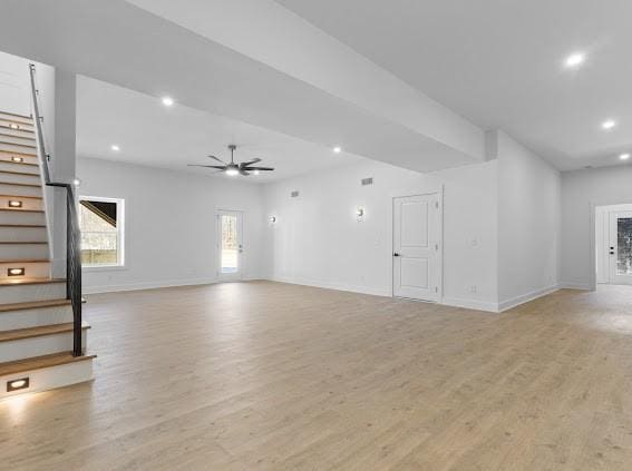 unfurnished living room with baseboards, a ceiling fan, light wood-style flooring, stairs, and recessed lighting