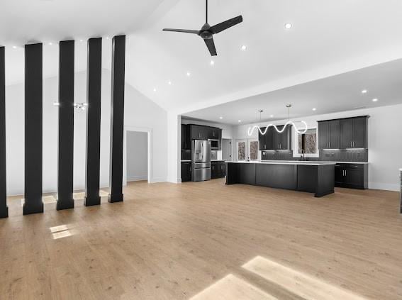 unfurnished living room featuring light wood finished floors, recessed lighting, a ceiling fan, high vaulted ceiling, and baseboards