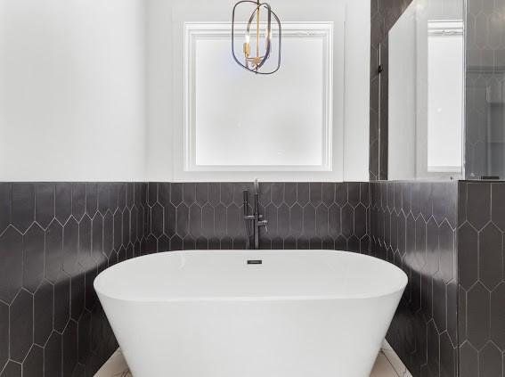 full bath with a freestanding bath and tile walls