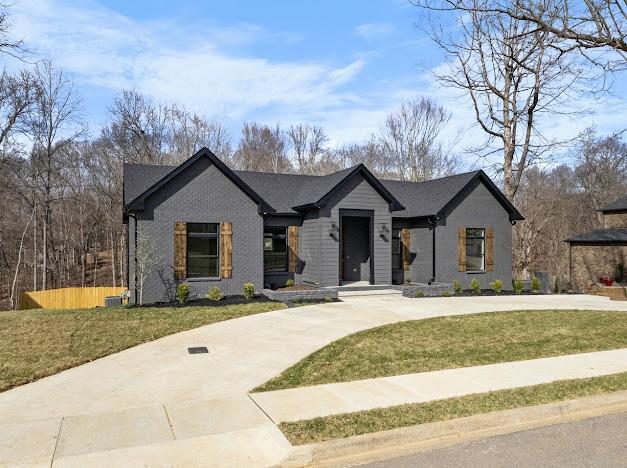 view of front of home with curved driveway, a front lawn, and fence