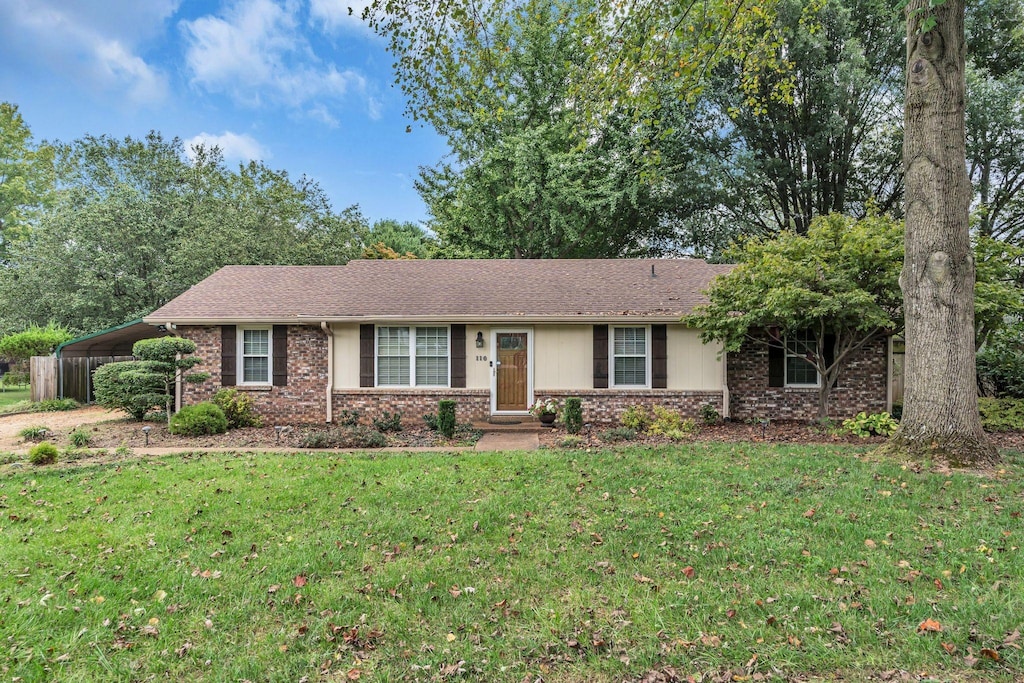 ranch-style house featuring a front lawn and a carport