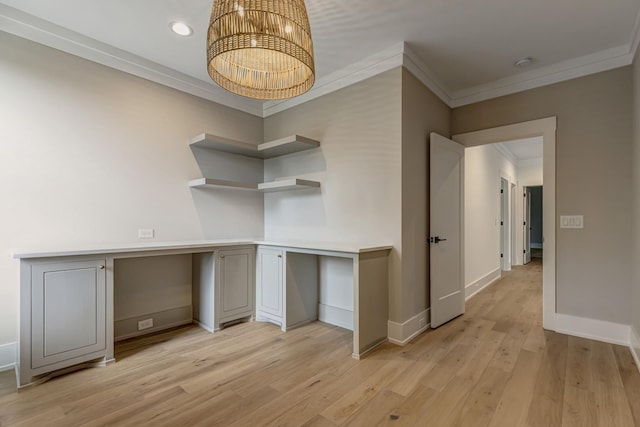 unfurnished office featuring built in desk, an inviting chandelier, ornamental molding, and light hardwood / wood-style floors