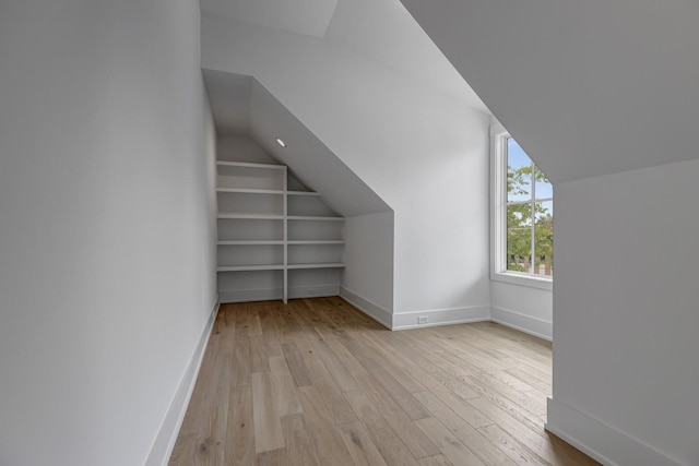 additional living space featuring vaulted ceiling, built in features, and light wood-type flooring