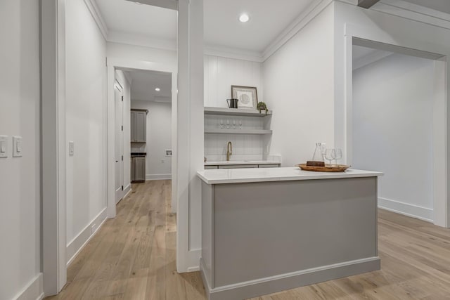 bar with decorative backsplash, sink, light hardwood / wood-style flooring, and crown molding