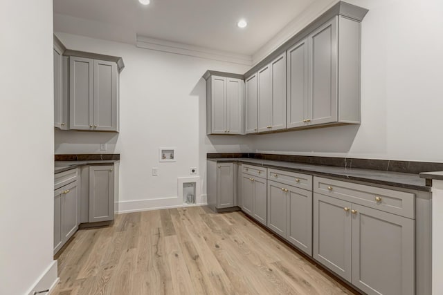 washroom with hookup for a washing machine, cabinets, hookup for an electric dryer, and light wood-type flooring