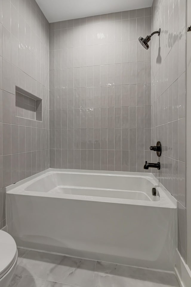 bathroom featuring toilet, tile walls, and tub / shower combination