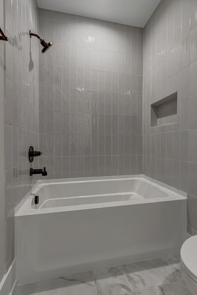 bathroom with toilet, shower / bath combination, and tile walls