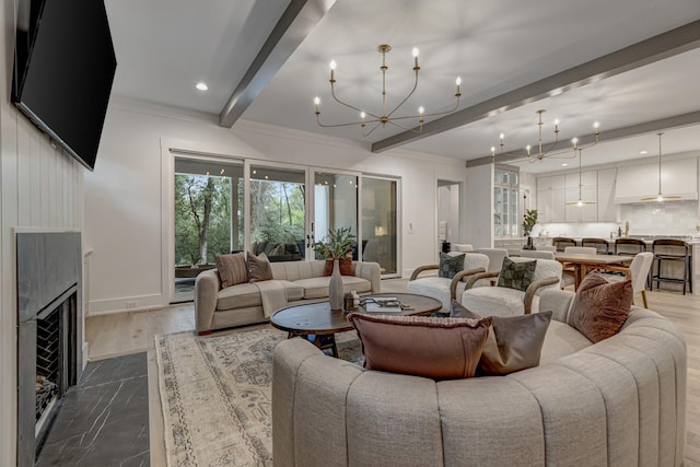 living room featuring beam ceiling, a premium fireplace, and ceiling fan with notable chandelier