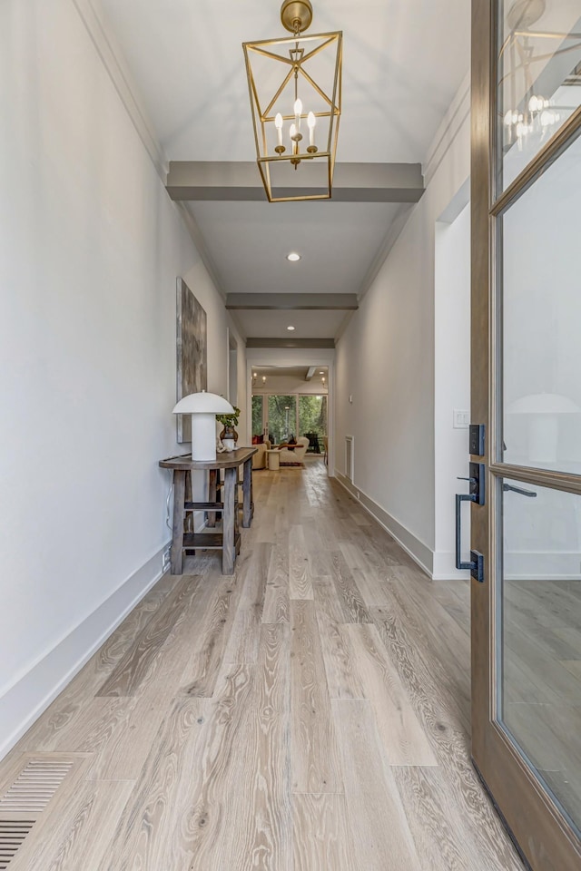 hallway featuring light wood-type flooring, an inviting chandelier, and ornamental molding