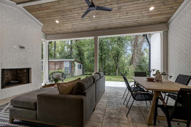 interior space featuring ceiling fan, wooden ceiling, lofted ceiling, and an outdoor brick fireplace