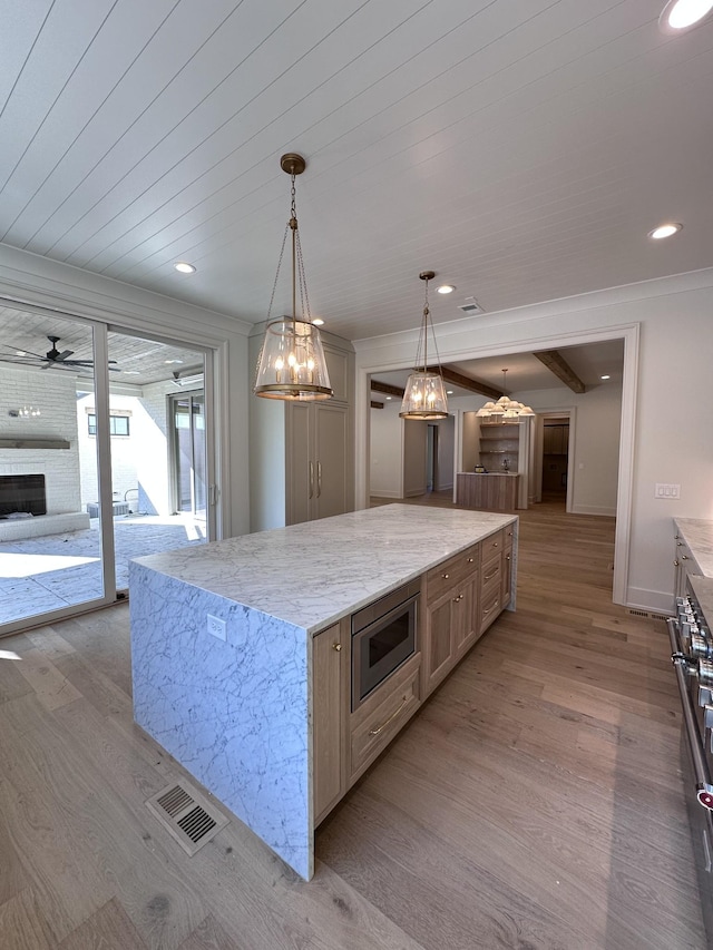 kitchen with light stone countertops, a spacious island, pendant lighting, and stainless steel appliances