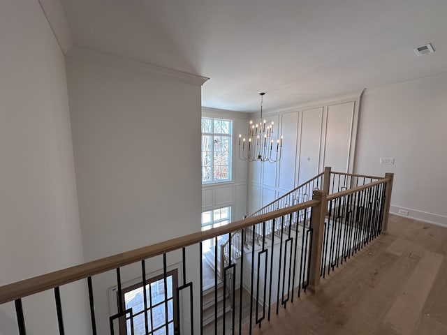 hallway featuring a chandelier, crown molding, and hardwood / wood-style floors