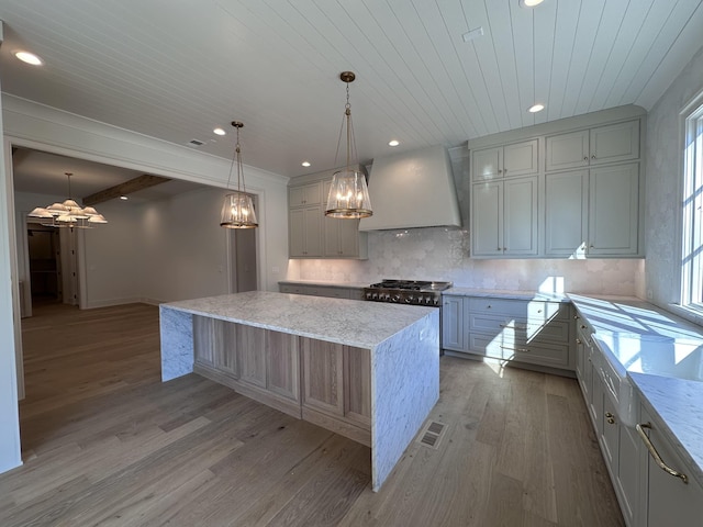 kitchen with light stone countertops, a center island, beamed ceiling, and custom exhaust hood