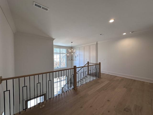 corridor featuring a notable chandelier, crown molding, and hardwood / wood-style floors