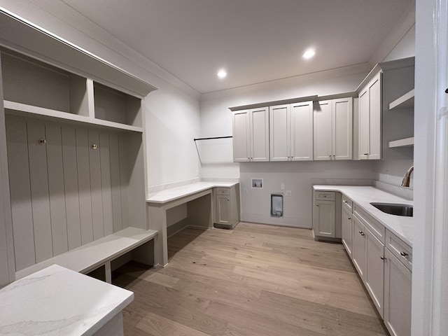 clothes washing area featuring light hardwood / wood-style floors, sink, crown molding, hookup for a washing machine, and cabinets