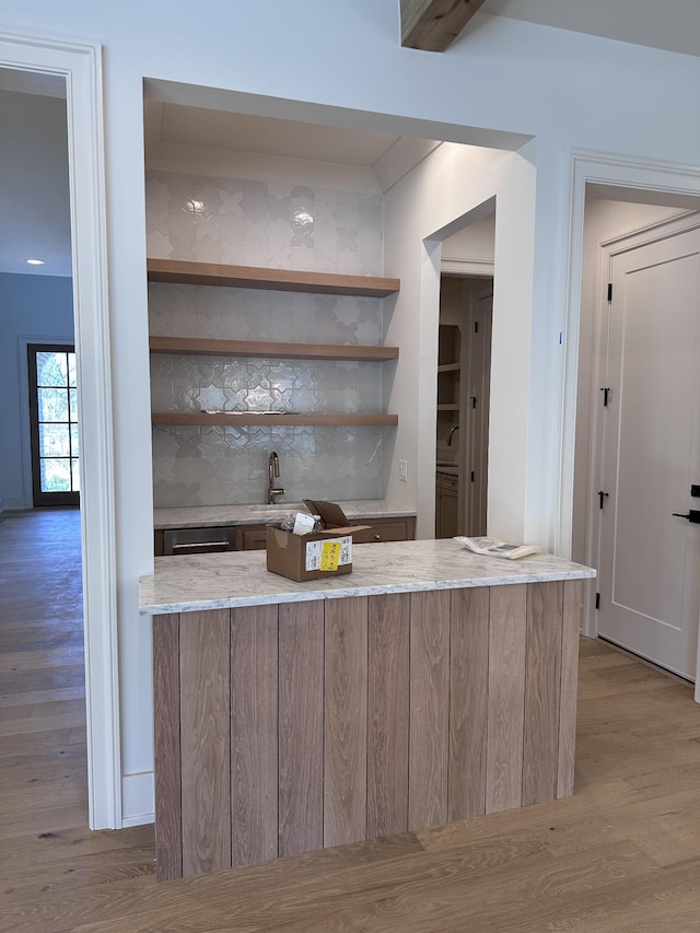 bar with light hardwood / wood-style flooring and sink